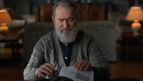 hombre viejo leyendo un documento en la sala de estar de lujo