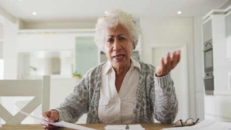 Portrait-of-african-american-senior-woman-holding-a-document-talking-looking-at-the-camera