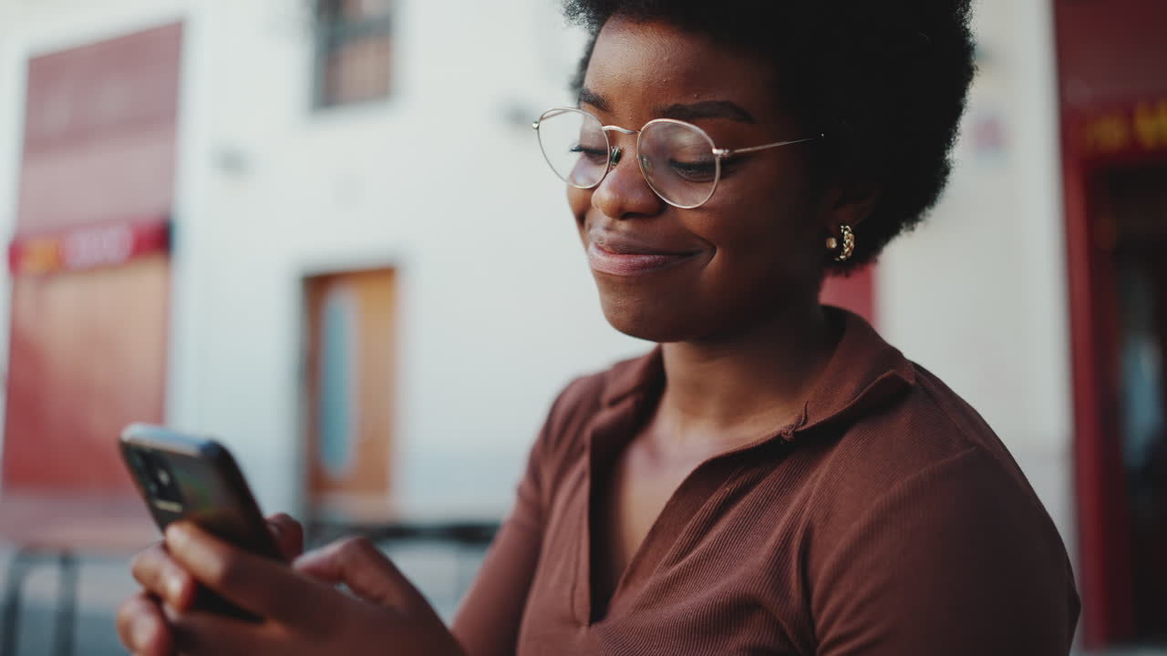 African girl holding smartphone looking happy outdoors