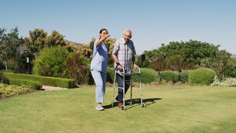 Video-of-happy-biracial-female-doctor-taking-care-of-caucasian-senior-man-in-rest-home-garden