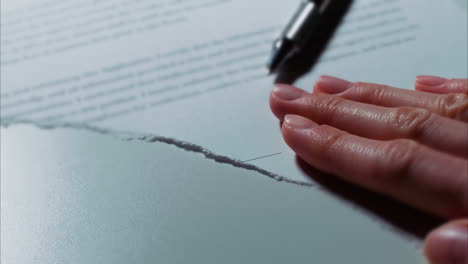 -Close-up-low-angle-shot-of-a-female-caucasian-hand-tearing-up-a-signed-document-or-contract