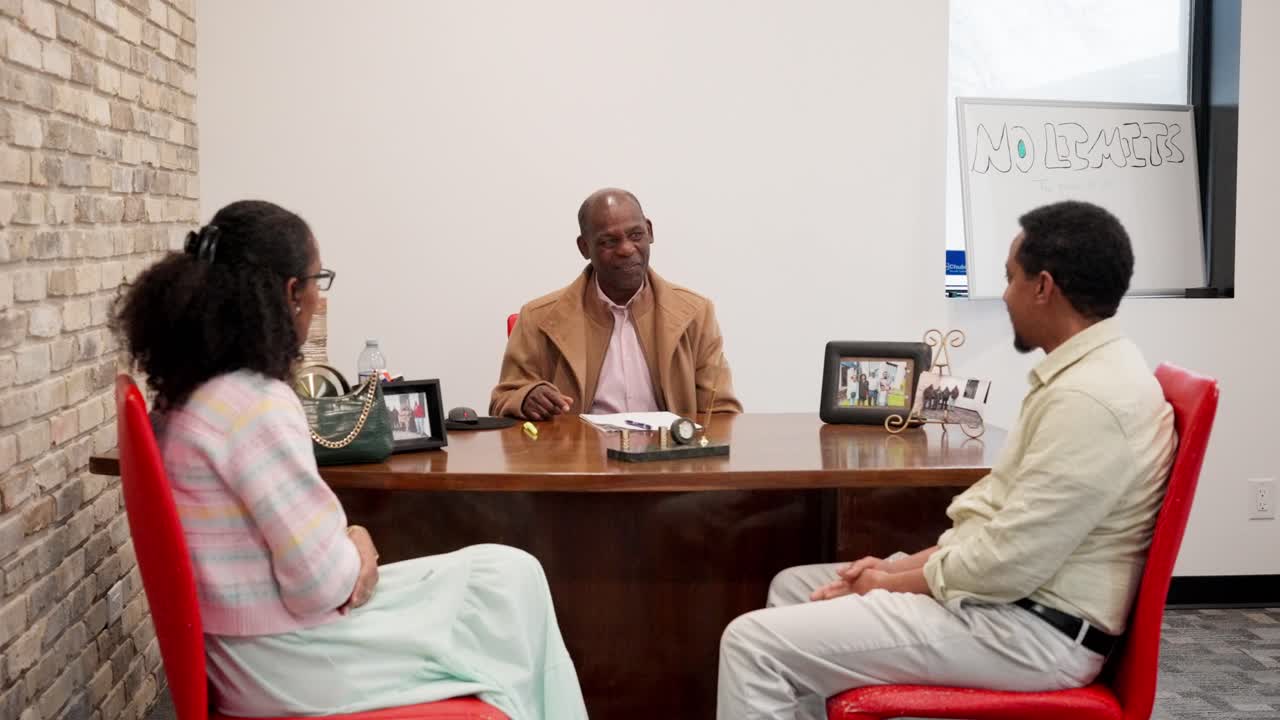 Well-dressed couple listens happily as senior advisor explains furniture features