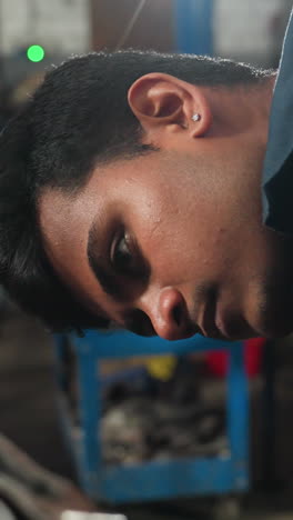 mechanic working diligently on engine block in automotive workshop, focusing on detailed repair and inspection, with partial view of observer hand in white glove in mechanical shop