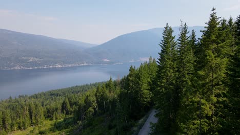 Imágenes-Aéreas-Que-Vuelan-A-Través-De-Un-Paisaje-Montañoso-Cubierto-Por-Dosel-De-Bosque-De-Coníferas-Sobre-El-Lago-Shuswap-Durante-La-Temporada-De-Incendios-Forestales