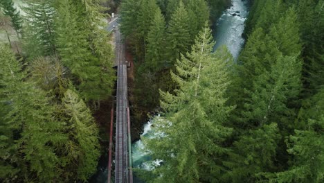 breathtaking flyover of railroad bridge spanning lewis river, combined pan and orbit