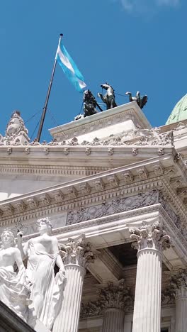 national congress building with argentine flag waving in blue skyline, daylight vertical view in buenos aires city