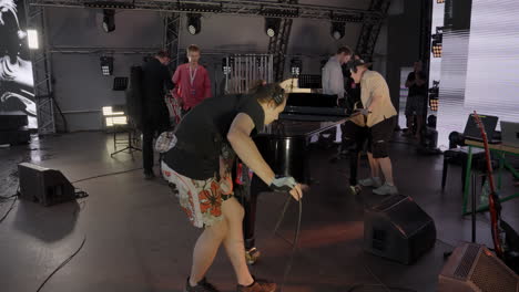 setting up a grand piano on stage for a music concert.