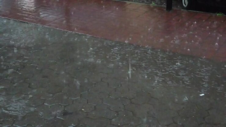 Rain in the city. Rain drops fall on the sidewalk.