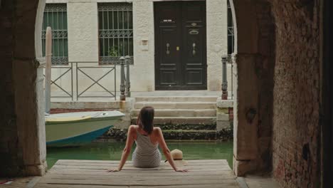 woman sitting in arch near canal