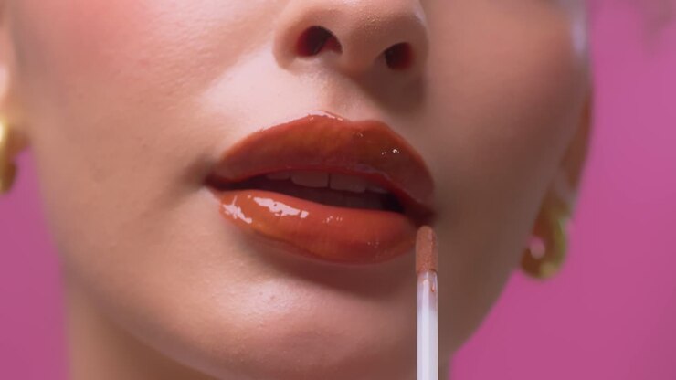 Bella donna che applica il lucidalabbra sulle sue labbra rosse e sensuali.