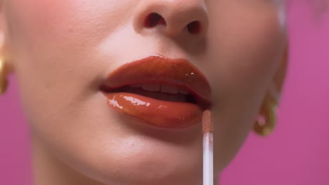 beautiful woman applying lip gloss on her sexy red lips