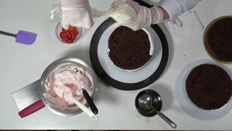 flat lay shot the baker uses a pastry bag to apply and decorate the cream on the cake.