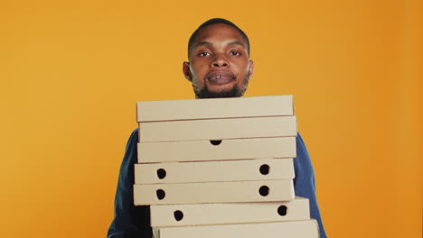 el mensajero de una pizzería afroamericana lleva un montón de pizzas para una entrega rápida.