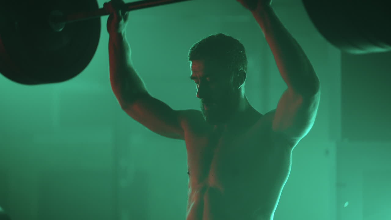 Athletic man lifting a barbell at gym during cross training. bodybuilder training using barbell weightlifting exercise muscular sportsman power lifting. Determined muscular man lifting heavy weights
