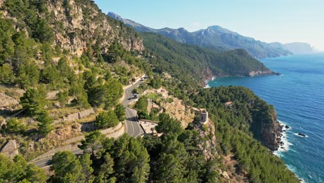 the coastline of sierra de tramuntana glows under a stunning sunset, highlighting the historic torre des verger as it overlooks the mediterranean sea.