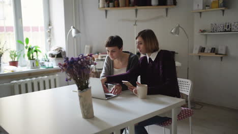 Zwei-Kreative-Frauen-Am-Tisch-Und-Mit-Notebook-Zum-Online-Einkauf