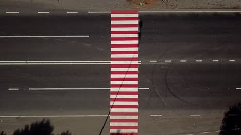 trucks are driving on the highway with a pedestrian crossing in red and white colours. Aerial view