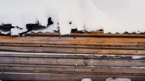 pila de tablones cubiertos de nieve al aire libre en invierno, camión aéreo a la izquierda
