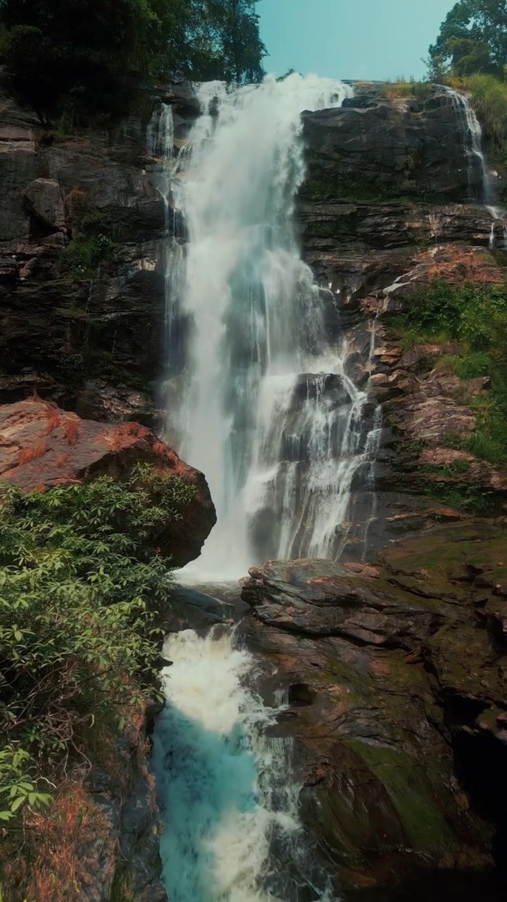 Cachoeira Poderosa Caindo em Cascata por um Penhasco Rochoso em uma Floresta Exuberante