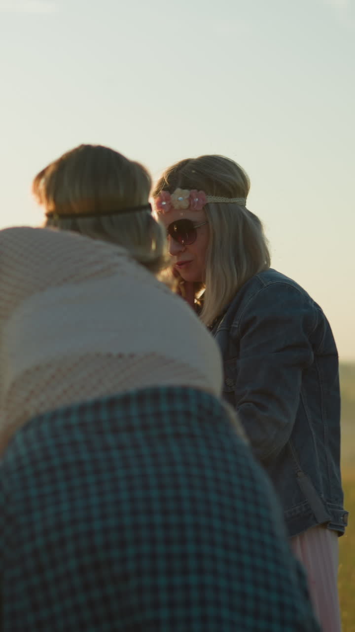 dos amigos están limpiando meticulosamente una bicicleta eléctrica roja en un campo abierto de hierba, uno se centra en limpiar el vidrio mientras el otro limpia el tanque, un casco cuelga en el espejo lateral