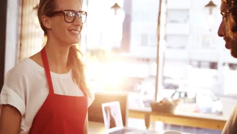 Waitress-serving-a-coffee-and-sandwich-to-customer-in-cafÃ©