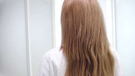 woman with long blonde hair in a white bathrobe in a bathroom
