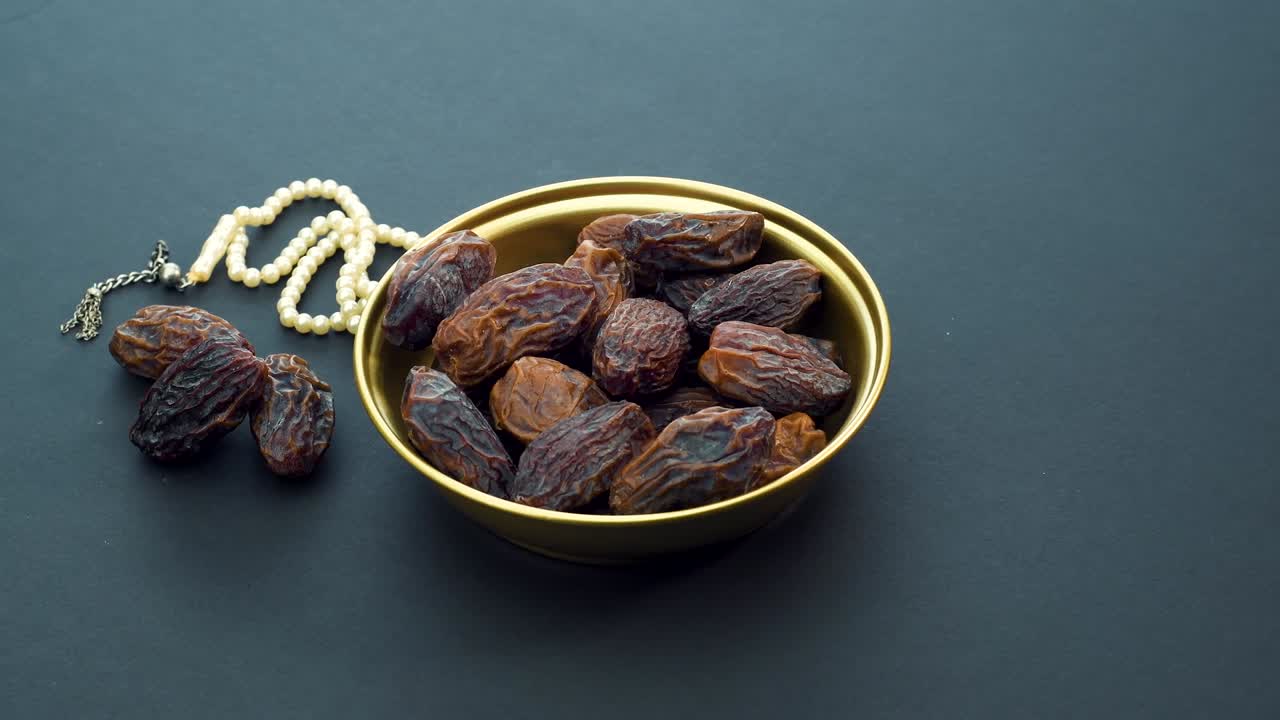 Date Fruit and Rosary on Black Background. Rotating on Turn Table. Iftar Food Mostly Eating in Ramadan. 4K Resolution.