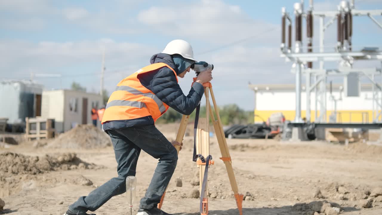 An engineer surveyor takes measurements at the construction of a transformer substation
