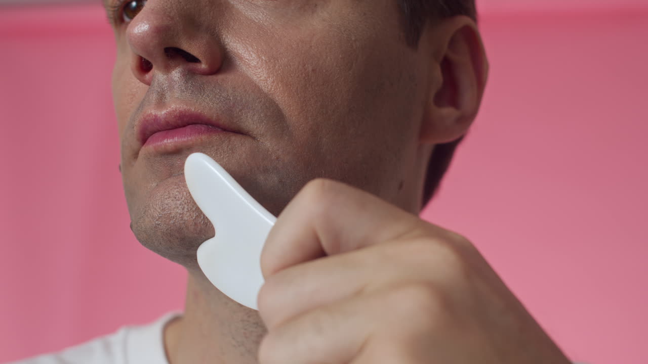Middle-aged Man Massaging Chin with Gua Sha Tool