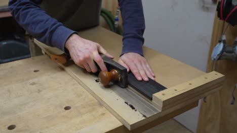 artesano usando un plano de madera en un trozo de madera de ébano para crear nuevos artículos