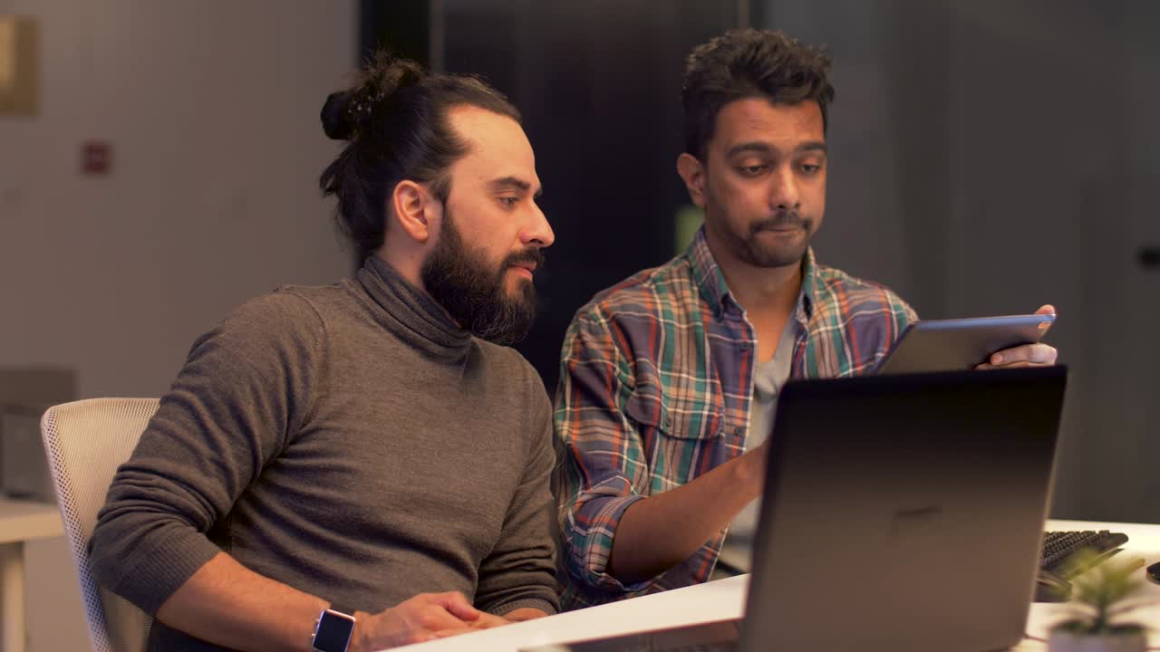 programmers with tablet computer working at night office