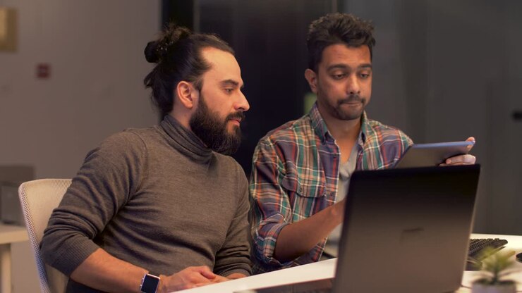 programmers with tablet computer working at night office