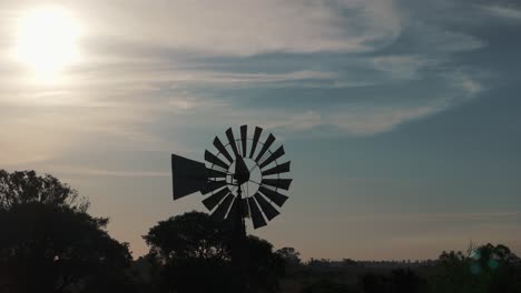 aerial view of rustic windmill silhouette at sunset on farm