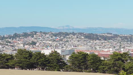 The slopes of Bernal Heights glow in afternoon light, showing colorful rooftops and winding residential streets.