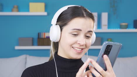 Portrait-of-young-woman-listening-to-music-and-looking-at-her-phone.