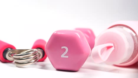 pink dumbbells, water bottle, and hand grip for home workout