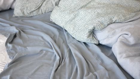 closeup of an unmade bed with blue and grey bedding