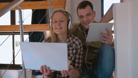 young couple in heaphones at home enjoying music