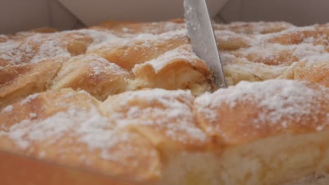fluffy golden-brown ensaimada from menorca being sliced, dusted with powdered sugar