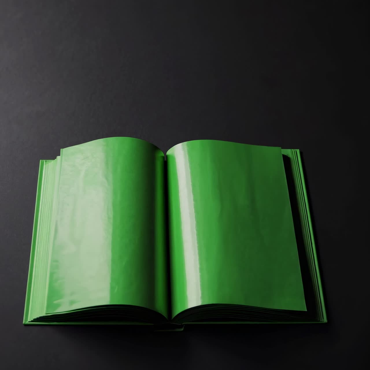 A video captures an open green book on a dark surface, shot from a high angle