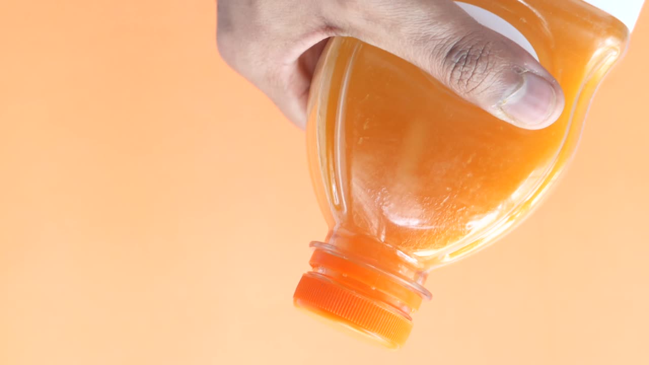 오렌지 주스 한 병을 들고 있는 손