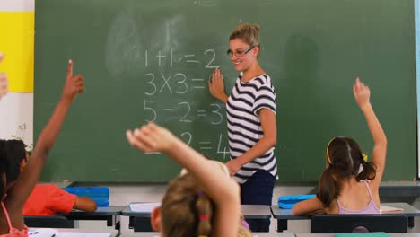 school kids raising hand in classroom