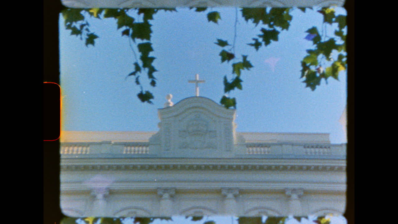 Vista architettonica vintage in Super 8mm di un campanile sotto le foglie.