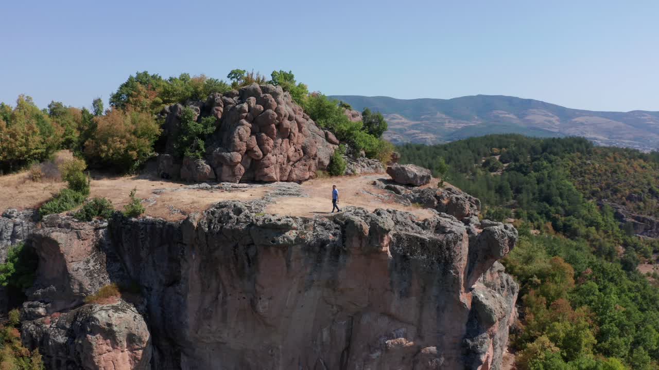 vista aérea de un viajero masculino caminando por una empinada meseta rocosa en el santuario tracio de harman kaya en bulgaria
