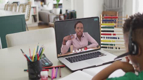 composition of biracial boy on laptop online learning with african american female teacher