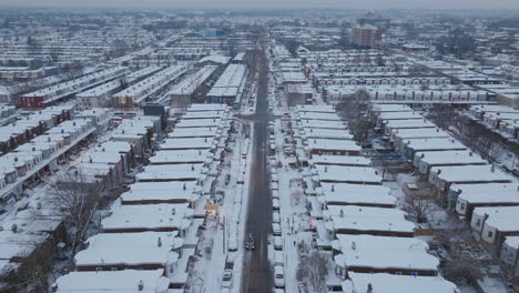 aerial drone footage flying down a street of historic row homes in snow covered neighborhoods in west philadelphia, pennsylvania as cars drive down deserted streets.