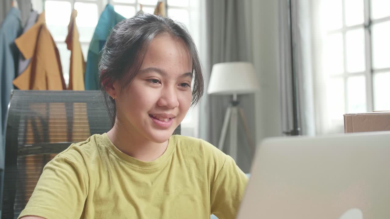 Close Up Of Asian Young Girl Online Seller Looking At Computer Screen While Selling Clothes At Home