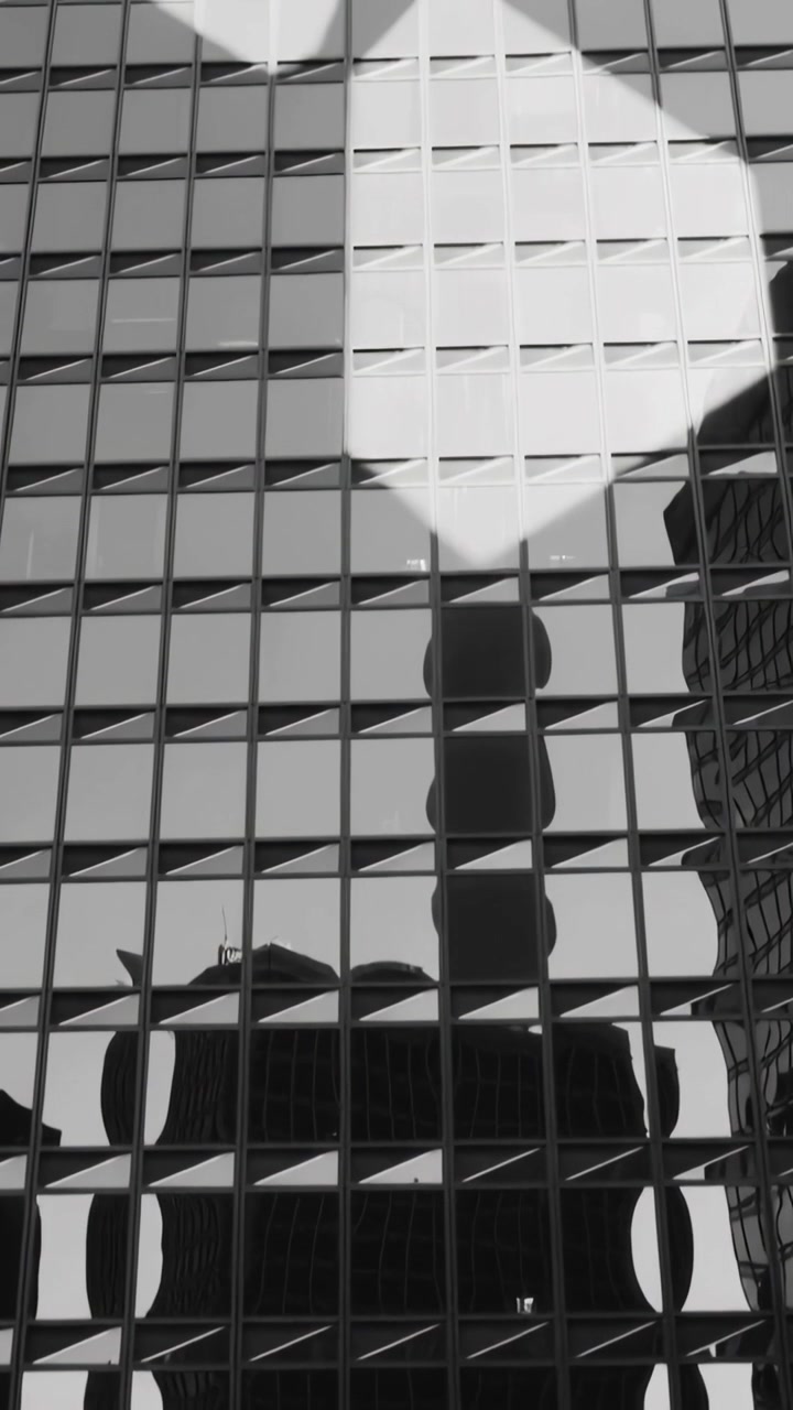 Video vertical: Reflejo cambiante cruzando el cristal en el centro, el sol incidiendo en los paneles, reflejando una torre