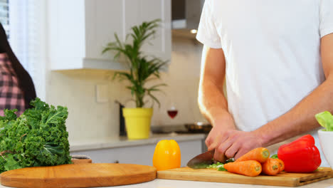 hombre cortando verduras y mujer embarazada lavando verduras de hojas en el fregadero 4k