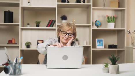 tired-old-woman-finishes-her-work-on-the-laptop-and-begins-massaging-her-temples,-trying-to-relieve-herself-from-a-headache-and-migraine